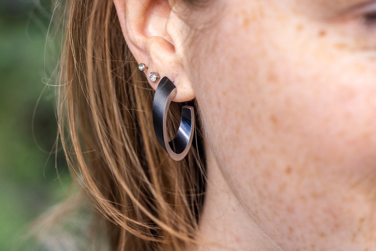OLIVIA Ohrstecker in Schwarz getragen | ovale Creolen mit matter Oberfläche | CLIC by Suzanne